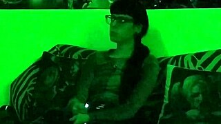 Beth, the kinky goth domina, smokes a cigarette in green light.