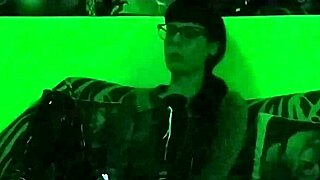 Beth, the kinky goth domina, smokes a cigarette in green light.